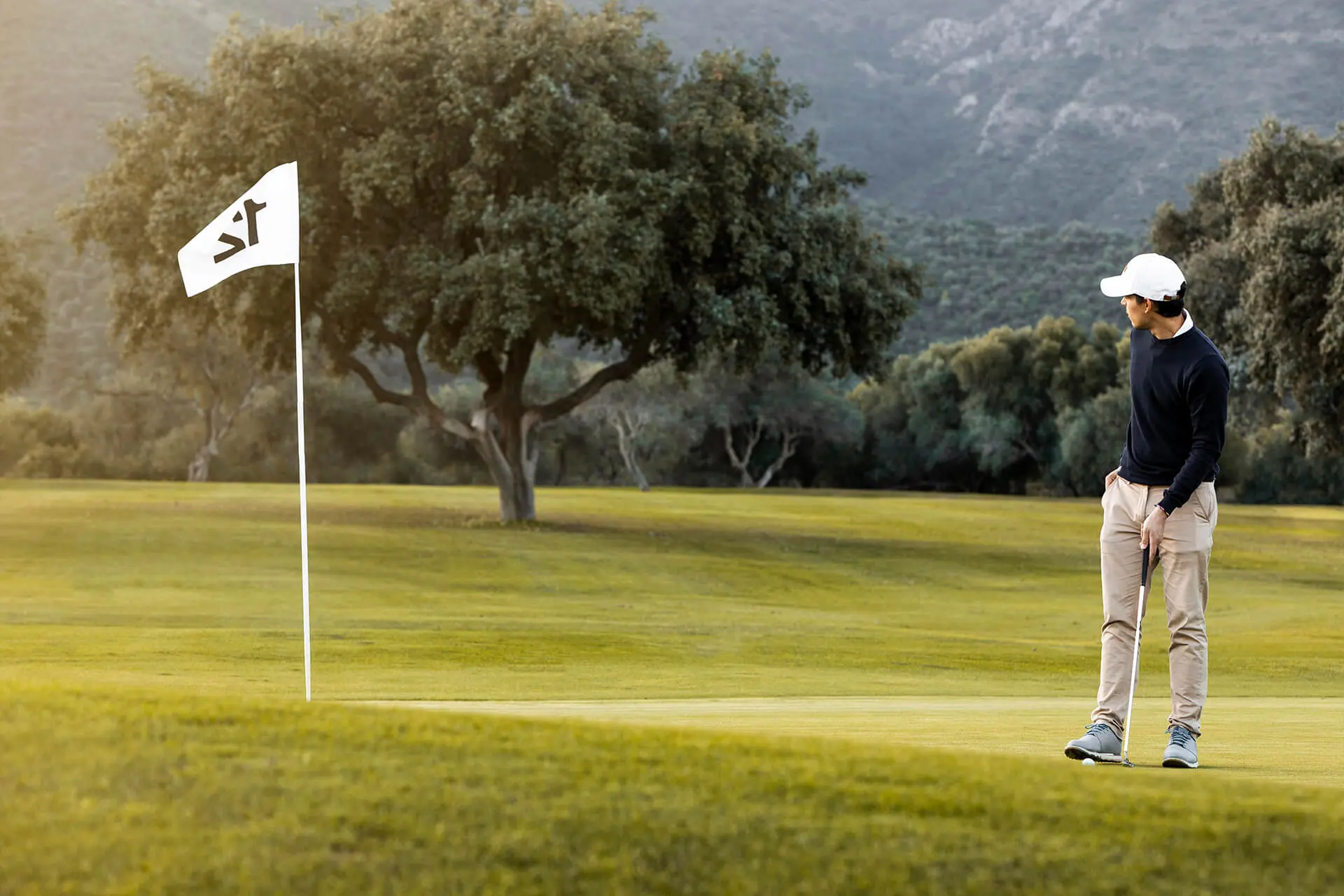 Man on the golf field next to a flag